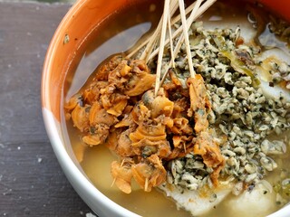 Authentic Lontong Kupang and Sate Kerang. A traditional clam soup with rice cakes in savory shrimp paste broth. Famous Indonesian street food specialty from Sidoarjo, East Java