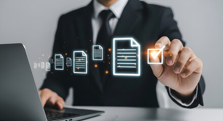Businessman reviewing digital documents, checking off a file, using a laptop.