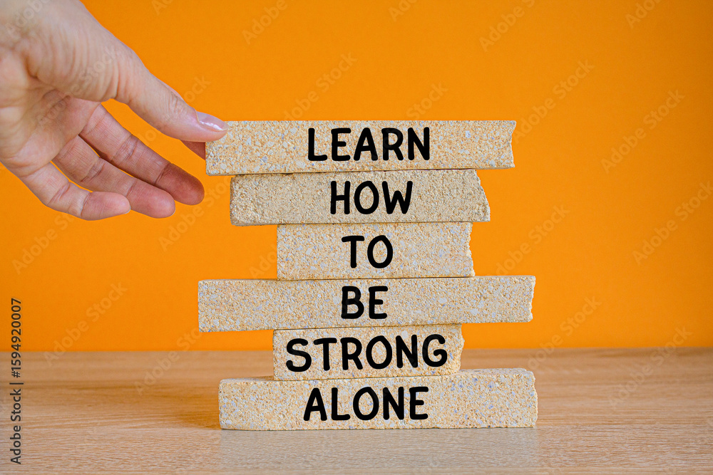 Fototapete learn how to be strong alone symbol. concept words learn how to be strong alone on brick blocks on a