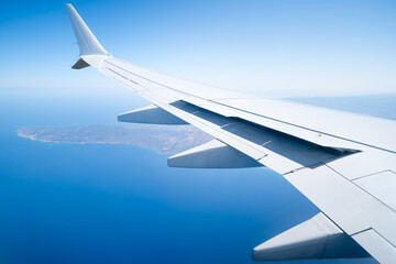 Airplane wing seen from a window. The plane flies over the holiday island of Cyprus. Travel concept