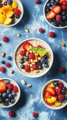 Vibrant breakfast scene with oatmeal topped with fresh berries, nuts, and basil leaf, surrounded by colorful fruit bowls on a dusty blue background with scattered ingredients