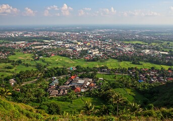 Naklejka premium 緑豊かな丘陵から望む、輝く街並み 広がる田園風景