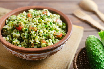 Oriental salad Tabbouleh in a ceramic bowl on a wooden table. Concept of traditional Lebanese or Syrian cuisine. Vegetarian or vegan dish. Rustic style. Selective focus. Horizontal orientation.