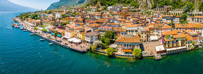 Naklejka premium Aerial view of Limone sul Garda, a colorful lakeside town in Italy nestled between Lake Garda and steep mountains under a bright blue sky