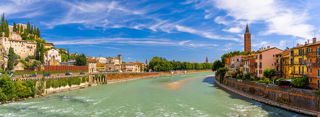 View of Ponte Pietra, Verona’s ancient Roman stone bridge crossing the Adige River under a clear sunny sky with historic buildings nearby
