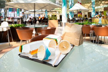 Fast food tray with empty packaging in a mall food court after lunch, showing real life dining...