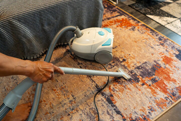 southeast asian man vacuuming abstract patterned rug in a modern minimalist house, with warm...