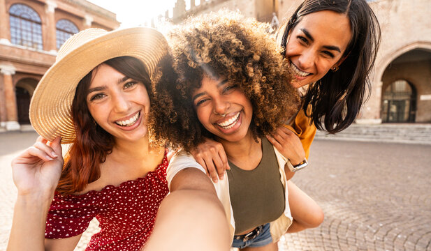 Happy multiracial women taking selfie picture with smart mobile phone outdoors - Cheerful female friends having fun on summer vacation - People life style concept with three girls hanging out