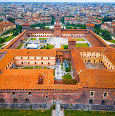 Historic Sforza Castle tower in Milan with medieval brickwork, large clock, and decorative details under a partly cloudy sky