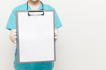 Healthcare professional in scrubs and gloves presenting a blank clipboard, suggesting space for...