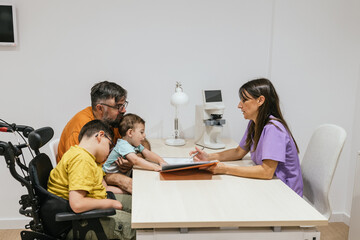 Optometrist explaining diagnosis to father and son with disability in wheelchair