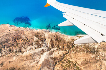 Airplane wing against turquoise sea background, Cyprus, travel concept.