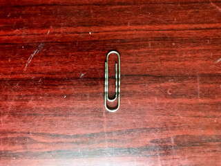 Metal paperclip on a wooden desk surface