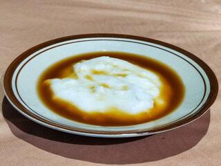 Bubur sumsum, traditional Indonesian food. Soft white marrow porridge served on a plate sprinkled...