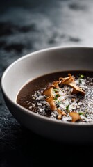 Gourmet black trumpet mushroom soup with smoked sea salt and truffle oil on matte stone background