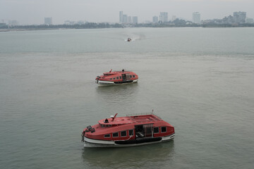 Red Lifeboats Floating on Calm Water with Cityscape in Background