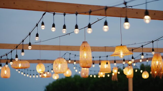 Outdoor string lights and woven rattan lamps create a warm, cozy ambiance for an evening garden party or rustic wedding setup.