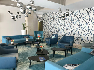Contemporary hotel lobby featuring elegant blue sofas and modern silver statement lighting — a stylish, tranquil space reflecting high-end hospitality design