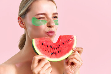 A delicious, juicy watermelon. A beautiful girl wearing green under-eye patches is eating...