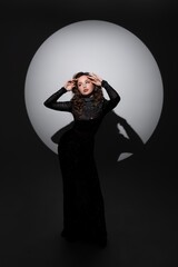 Girl in long black dress standing near circle in studio