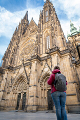 Mujer turista con mochila caminando en la fachada de la Catedral de Praga un día soleado
