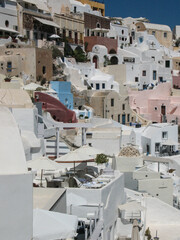 Vibrant colorful houses and terraces in Santorini, Greece, bathed in warm afternoon light. Traditional Cycladic architecture and sea glimpses create a lively and charming Mediterranean scene.