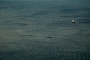 A small sailboat floating alone on the calm deep blue Aegean Sea under a clear bright sky. Peaceful...
