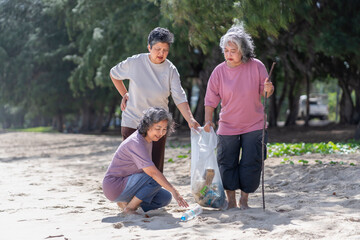 asian senior women as the volunteers putting trash in a garbage bag collecting waste,elderly...
