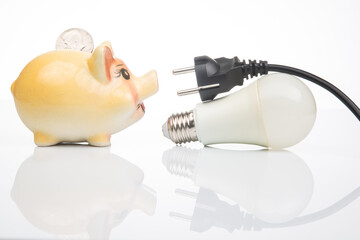 Piggy bank, LED lamp and electric cable plug. Saving electricity. Energy saving concept