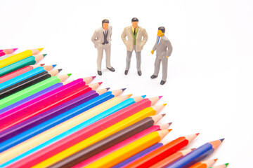 Brightly colored pencils fanned out on a white backdrop, paired with three miniature business...
