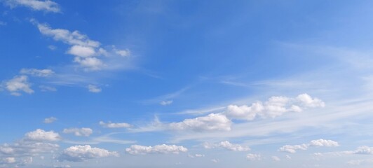 Panoramic cloudscape in clear blue sky in summer. Nature sky background with fluffy clouds.