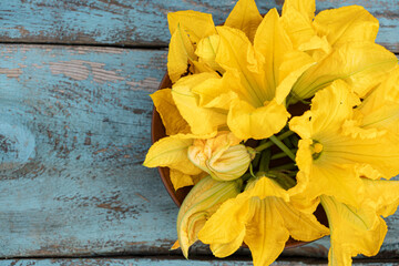 Bright yellow squash blossoms create a stunning centerpiece on a rustic wooden table in bright natural light