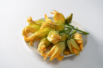 Vibrant zucchini blossoms elegantly arranged on a white plate, showcasing nature's artistry and culinary potential in a kitchen setting