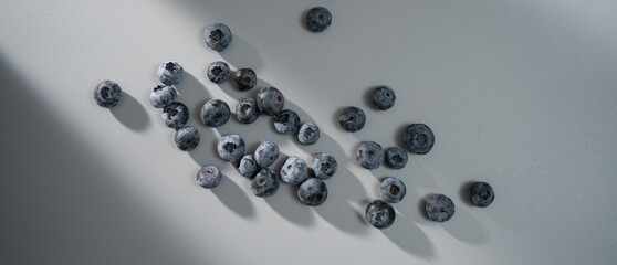 Fresh blueberries scattered on a light surface creating intriguing shadows in soft afternoon light