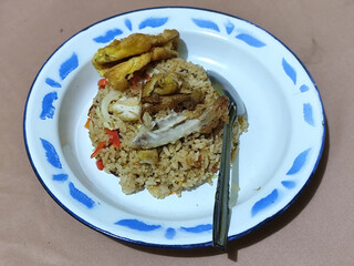 Fried rice with omelet, chicken pieces and red chili slices, has a delicious taste, served on a classic iron plate, with a brown background.
