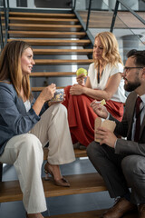 Business people enjoying lunch break on office staircase