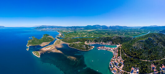 Aerial panorama of Blace village and Neretva River delta, showing coastline, green valley, and turquoise Adriatic Sea under clear summer sky © marinv