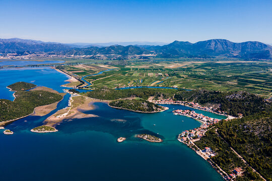 Aerial panorama of Blace village and Neretva River delta, showing coastline, green valley, and turquoise Adriatic Sea under clear summer sky