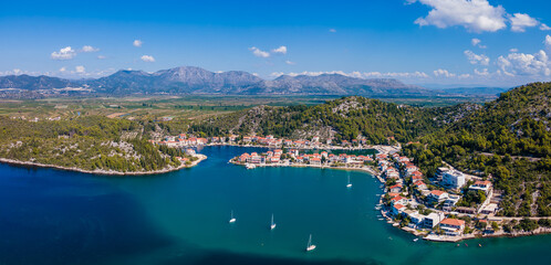 Fototapeta premium Aerial panorama of Blace village and Neretva River delta, showing coastline, green valley, and turquoise Adriatic Sea under clear summer sky