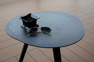 elegant sunglasses and ashtray on a modern black patio table