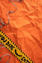Bright vertical orange crumpled paper with scary caution tape and wire for Halloween decor
