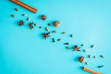 Assorted winter spices—cinnamon sticks, star anise, nutmeg, cardamom and cloves—scattered...