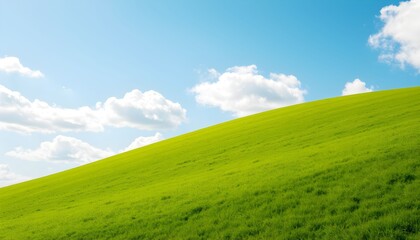 Lush green hill sloping gently under a vibrant blue sky dotted with fluffy white clouds.