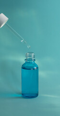 Gotero sobre una botella azul de ácido hialurónico en fondo acuático