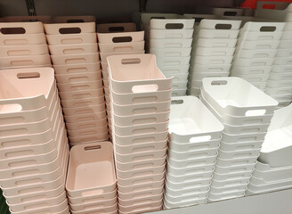 Stacked plastic storage bins in soft pink and white colors arranged neatly on shelves, showcasing...