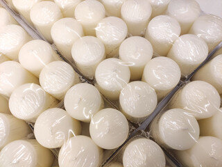 White candles neatly arranged in packaging, showcasing their smooth texture and uniform shape,...
