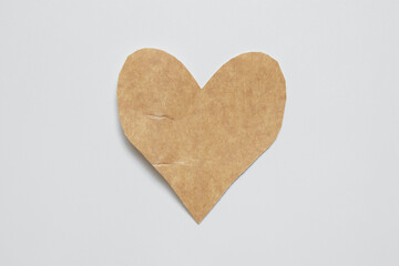 Brown craft paper heart cut with scissors on white background for valentine