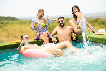 A lively pool scene with friends laughing, splashing water, and enjoying drinks while having a...