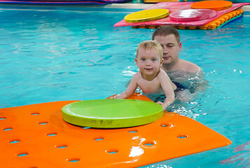 A man is holding a baby on a pool float