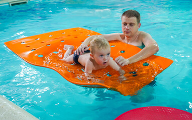 A man is holding a baby on a pool float